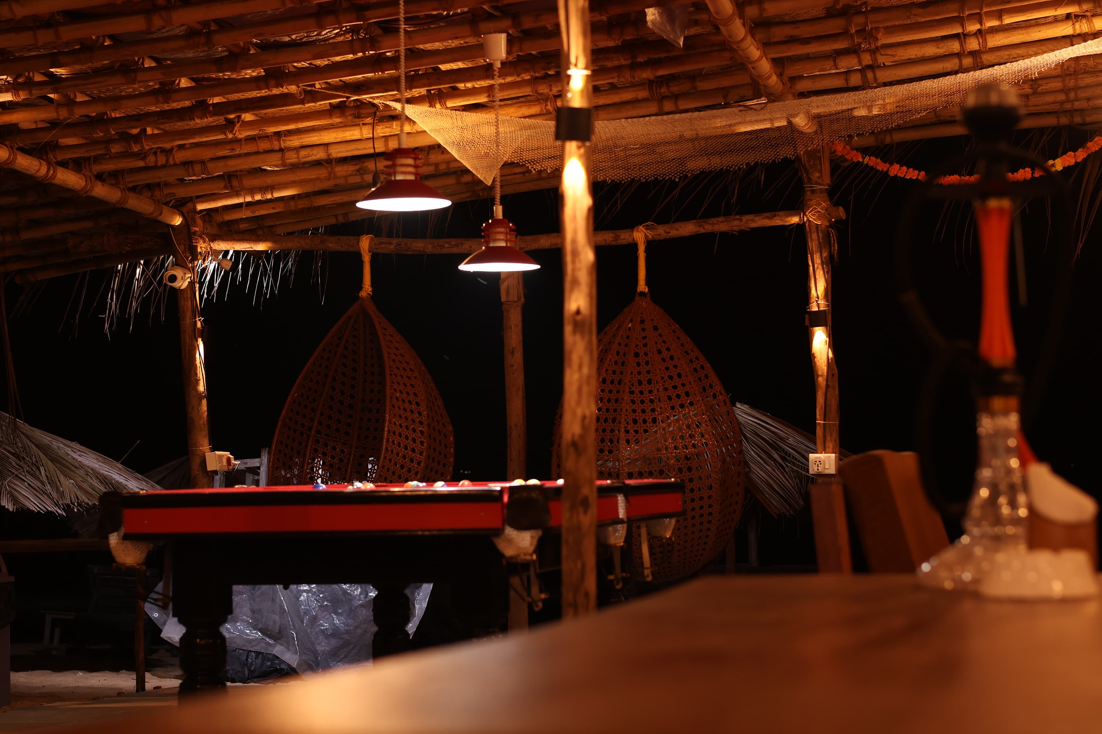 Pool table and hanging chairs in a thatched evening lounge